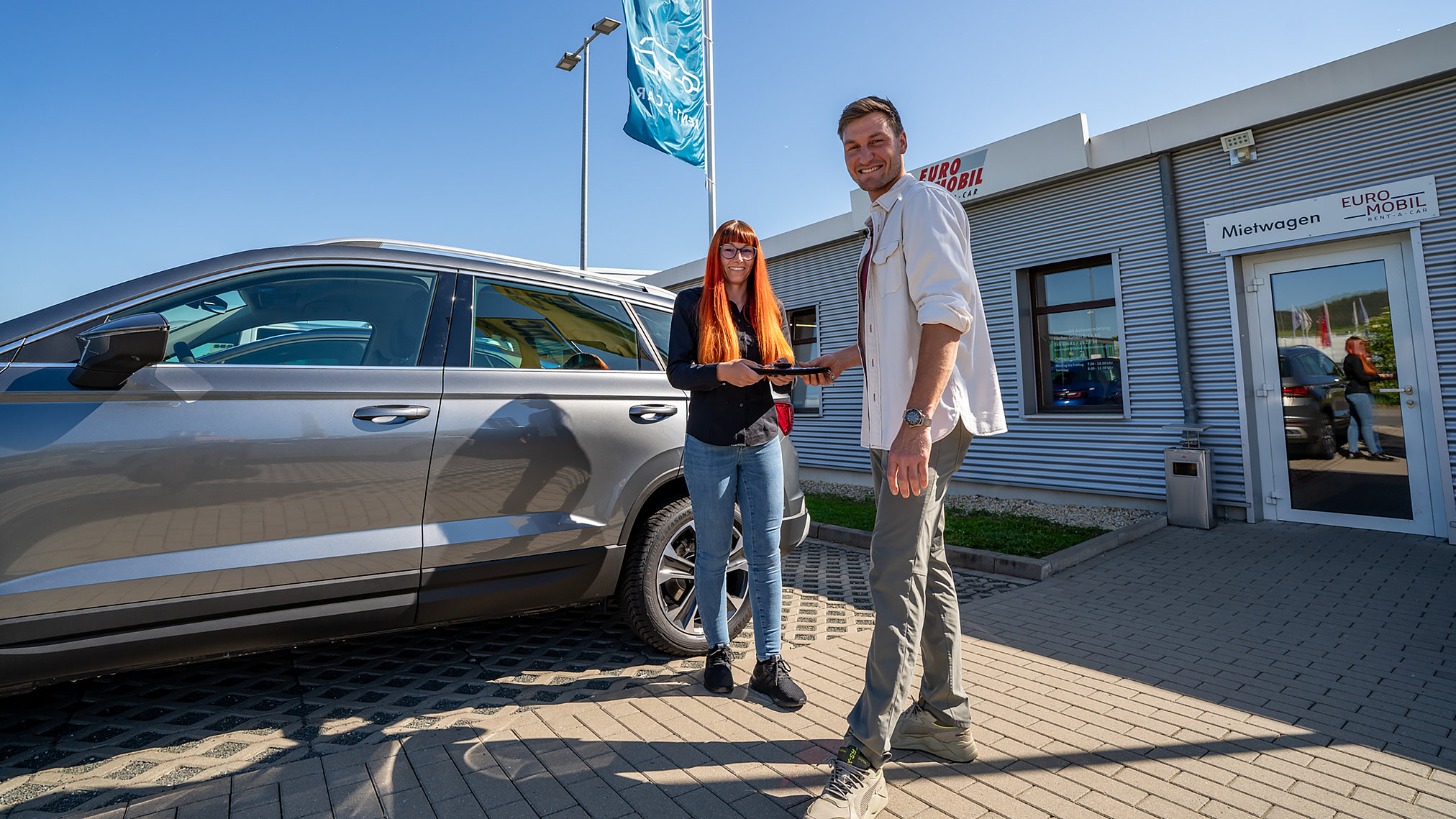 Mietwagenübergabe bei EUROMOBIL am Autohaus Fischer mit Kundin, Kunde und Fahrzeug